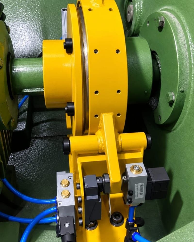 Bloco de válvula pneumática de segurança amarelo instalado no freio-embreagem de uma prensa, com mangueiras azuis